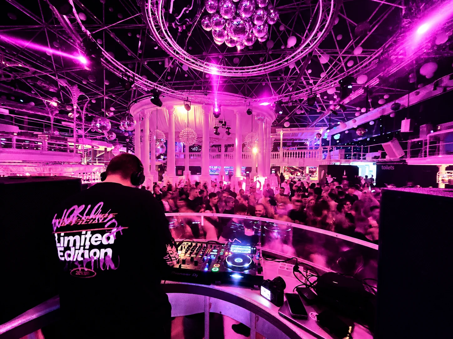 Paulyy Pudd behind the DJ decks overlooking a busy Ibiza club