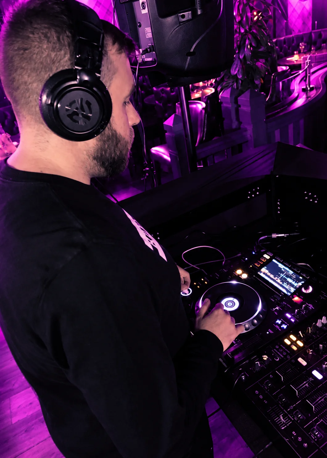 Paulyy Pudd in profile wearing headphones and operating DJ decks
